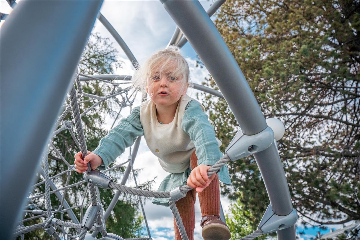 Jente på 3 år som klatrer i lekestativ - Klikk for stort bilde